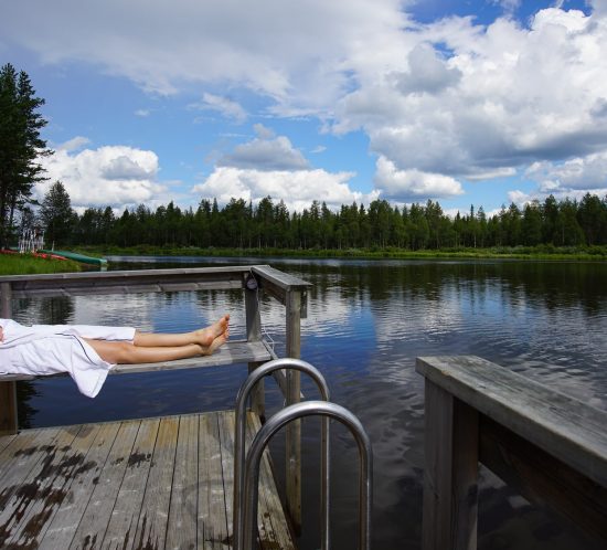 Mann im Bademantel liegt auf Bank am See © Tarja Prüss